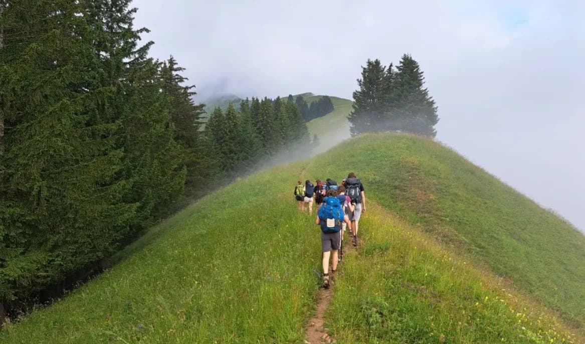Groupe de randonneurs sur une crête herbeuse dans la brume, massif des Bauges